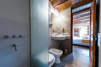 a bathroom with a toilet and a sink and a bed at Portal del Lago Hotel in Villa Carlos Paz