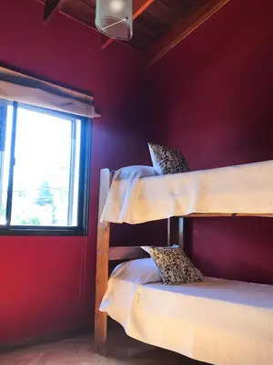 two bunk beds in a red room with a window at Hermosa casa con vista al lago in Villa Carlos Paz