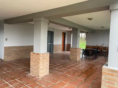 a porch with a brick floor and columns and a table at Hermosa casa con vista al lago in Villa Carlos Paz