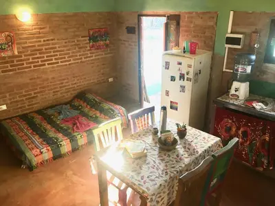 a dining room with a table and a refrigerator at Pintoresca Cabaña Céntrica a pasos del río Mina Clavero in Mina Clavero