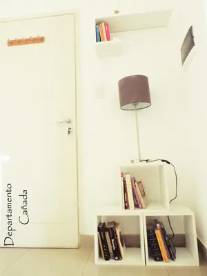 a lamp sitting on a white shelf with books at Departamento Cañada Güemes
