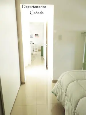 a bedroom with a bed and a hallway with a table at Departamento Cañada Güemes