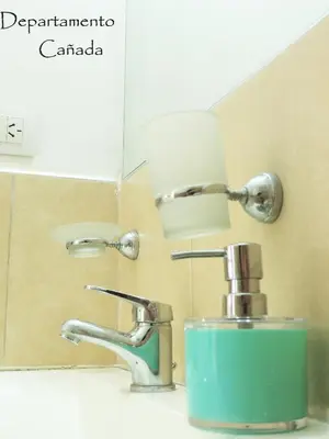 a bathroom sink with a blue soap dispenser next to a faucet at Departamento Cañada Güemes