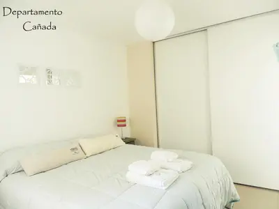 a white bedroom with a bed with towels on it at Departamento Cañada Güemes