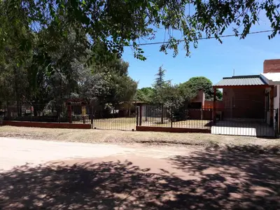 a fence in front of a building with trees at Cabañas Suave Remanso in Villa Cura Brochero