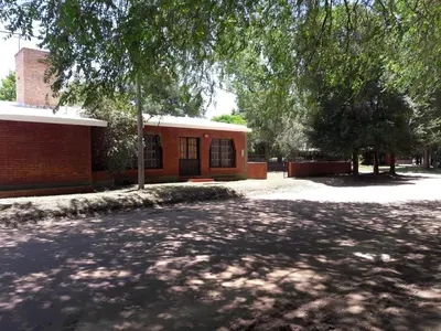 a brick building with a tree in front of it at Cabañas Suave Remanso in Villa Cura Brochero