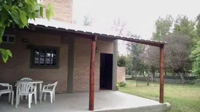 a patio with a table and chairs and a building at Cabañas Suave Remanso in Villa Cura Brochero