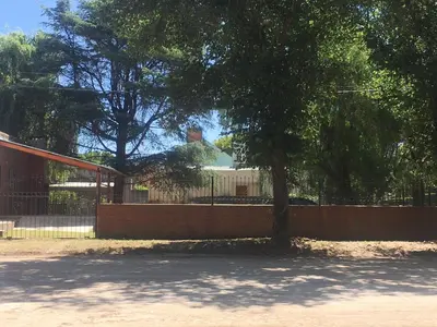 a fence with a tree in front of a building at Cabañas Suave Remanso in Villa Cura Brochero