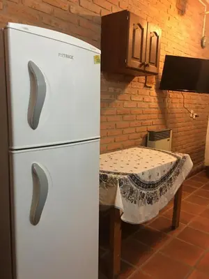 a white refrigerator in a kitchen with a table at Cabañas Suave Remanso in Villa Cura Brochero