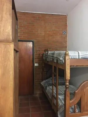 a room with two bunk beds and a brick wall at Cabañas Suave Remanso in Villa Cura Brochero