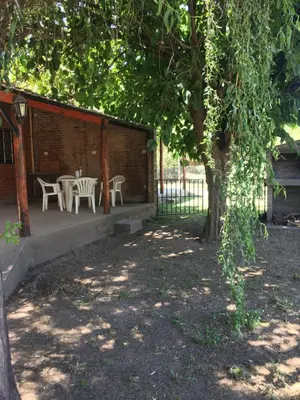 a patio with a table and chairs under a tree at Cabañas Suave Remanso in Villa Cura Brochero