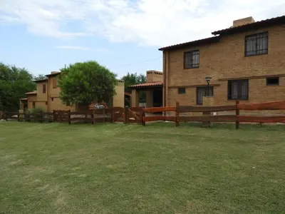 a fence in front of a building with a yard at CABAÑAS AGUARI in Santa Rosa de Calamuchita
