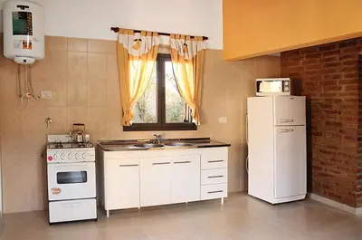 a kitchen with a white refrigerator and a sink at CABAÑAS AGUARI in Santa Rosa de Calamuchita