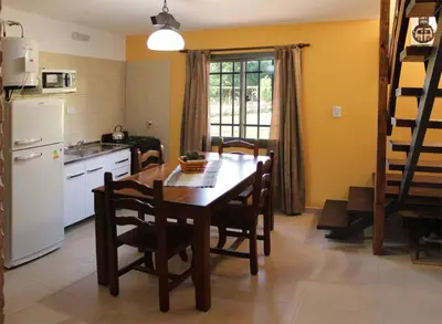 a kitchen with a table and chairs and a refrigerator at CABAÑAS AGUARI in Santa Rosa de Calamuchita