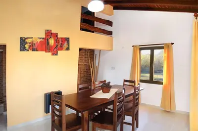 a dining room with a wooden table and chairs at CABAÑAS AGUARI in Santa Rosa de Calamuchita