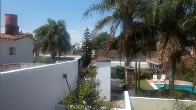a view of a house with a pool and palm trees at Ignacio Garzón Departamento in Cordoba