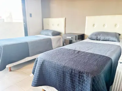 a bedroom with two beds with blue sheets on them at Constantino Iii in Villa Carlos Paz