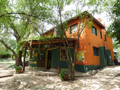 an orange and green building with trees at Casa Grande Hostel in Merlo