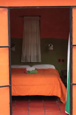 a bedroom with an orange bed with a window at Casa Grande Hostel in Merlo