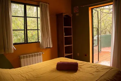 a bedroom with a bed and a large window at Casa Grande Hostel in Merlo