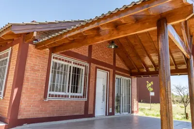 a brick house with a wooden roof and a white door at Cabañas Doña Juana in Nono