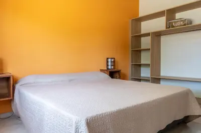 a bedroom with a white bed and an orange wall at Cabañas Doña Juana in Nono
