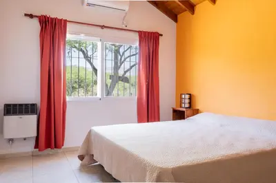 a bedroom with a bed and a window with red curtains at Cabañas Doña Juana in Nono