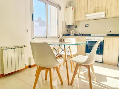 a kitchen with a glass table and two white chairs at Miralejos Ii in Villa Carlos Paz