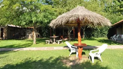 a table and chairs under a straw umbrella in a yard at El Rincón de Iri-Nan in Merlo