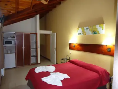 a bedroom with a red bed with towels on it at Posada Los Alamos in Merlo