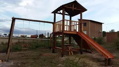 a wooden playground with a slide in a yard at Estancia de Campo in Estancia Vieja