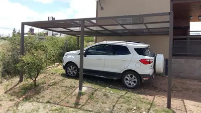 a white car parked under a cover in front of a house at Estancia de Campo in Estancia Vieja