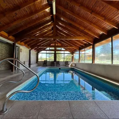 a swimming pool with a wooden ceiling and windows at Cabañas Steinhaus in Villa General Belgrano