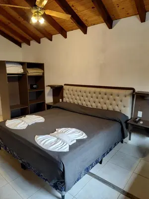 a large bed in a room with a wooden ceiling at Rancho Grande Hotel in Villa General Belgrano