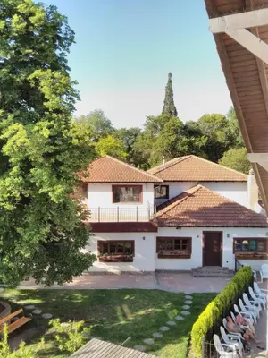 a large white house with a yard with chairs at Rancho Grande Hotel in Villa General Belgrano