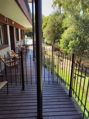 a porch with tables and chairs and a fence at Rancho Grande Hotel in Villa General Belgrano