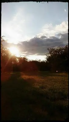 a sunset in a field with the sun setting at Cabaña Anita in Merlo
