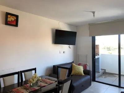 a living room with a dining table and a television at Edificio Tempo in Villa Carlos Paz