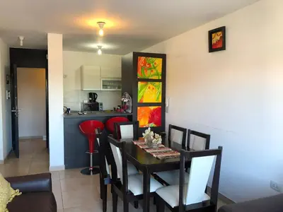 a dining room with a table and chairs and a kitchen at Edificio Tempo in Villa Carlos Paz
