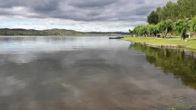 a large body of water with trees on the shore at Cabaña Trapiche San Luis in Trapiche