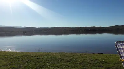 a view of a lake with a chair in the grass at Cabaña Trapiche San Luis in Trapiche