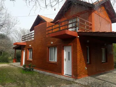 a brick house with a balcony on top of it at Cabañas Peñihue in Carpintería