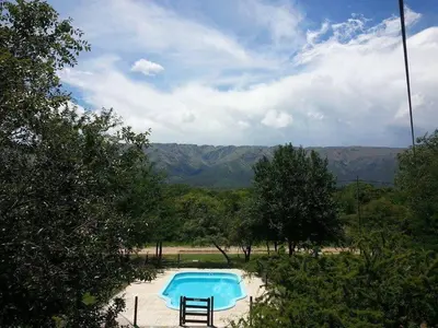 a blue swimming pool with trees and mountains in the background at Cabañas Peñihue in Carpintería