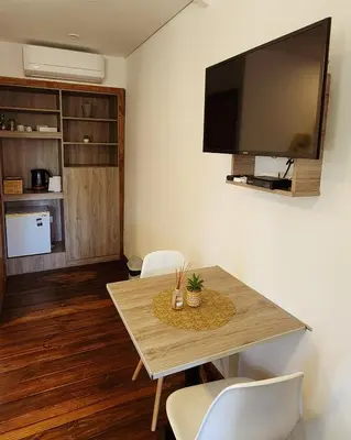 a living room with a table with chairs and a flat screen tv at Cabañas Cultura Serrana in Santa Rosa de Calamuchita