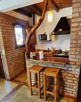 a kitchen with a counter and two stools in it at Cabañas Cultura Serrana in Santa Rosa de Calamuchita