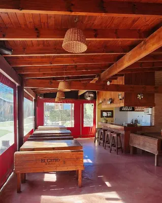 a room with wooden ceilings and a kitchen with tables at Cabañas Cultura Serrana in Santa Rosa de Calamuchita