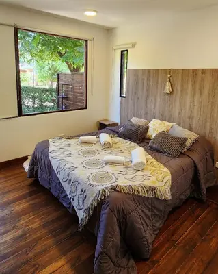 a large bed in a bedroom with a large window at Cabañas Cultura Serrana in Santa Rosa de Calamuchita