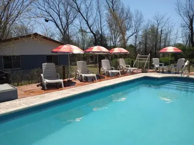 a swimming pool with chairs and umbrellas at Cabañas La Herradura in Villa Ciudad Parque