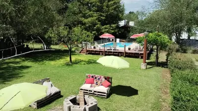 a yard with a pool and some chairs and umbrellas at Cabañas La Herradura in Villa Ciudad Parque