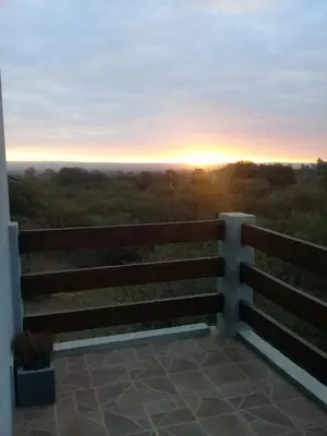 a view of the sunset from a fence with a bench at Cabaña Negusa in Merlo